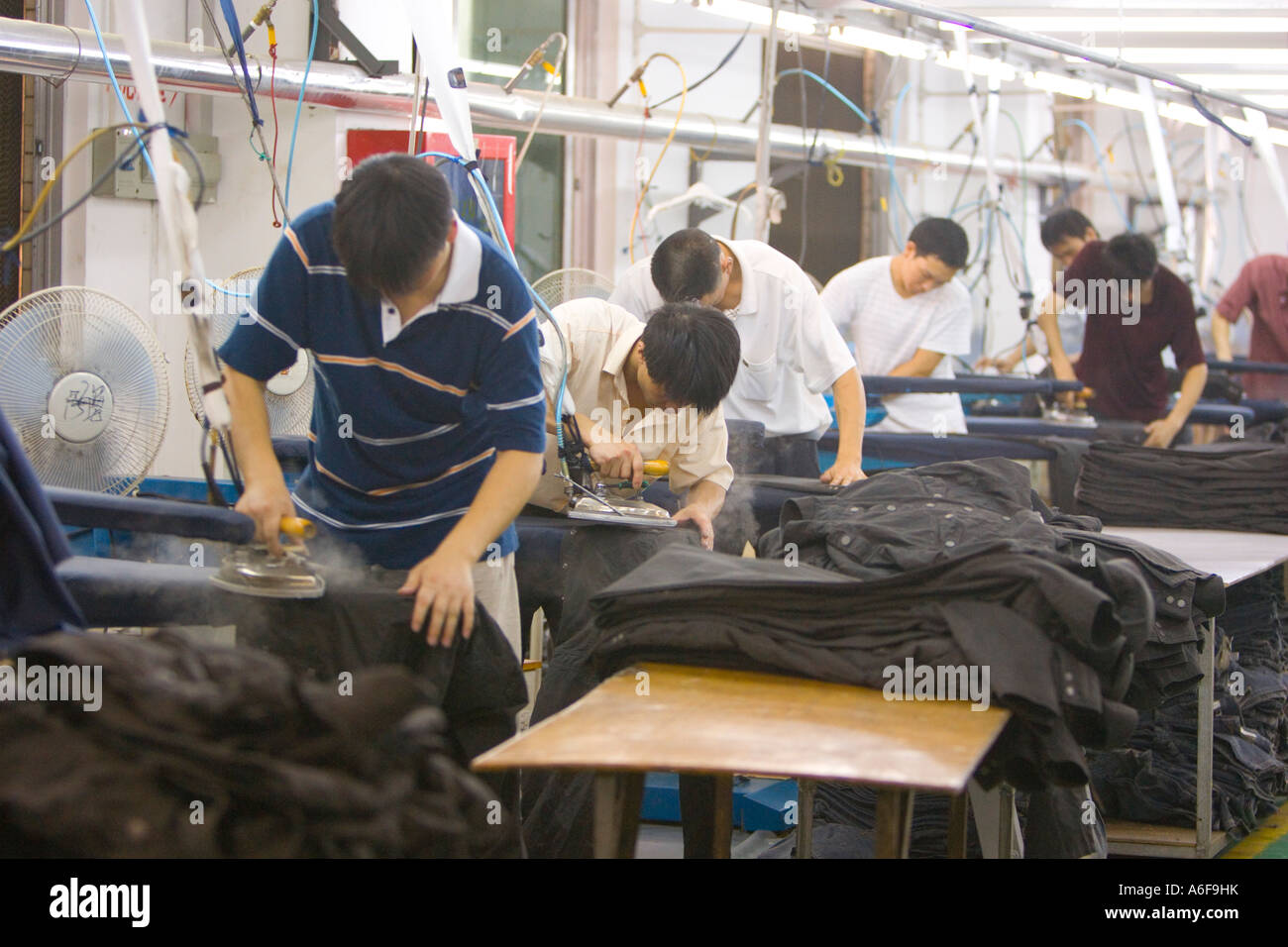 SHENZHEN GUANGDONG PROVINCE CHINA Men ironing finished clothing in a