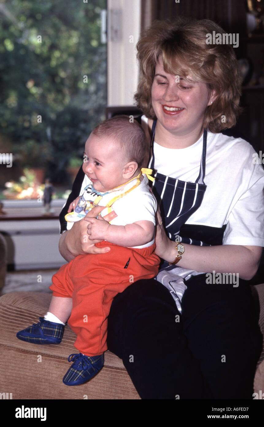 Mother & child 1996 indoors both model released twenty four year old mother in apron holding 19 week old baby boy in infant clothing Essex England UK Stock Photo