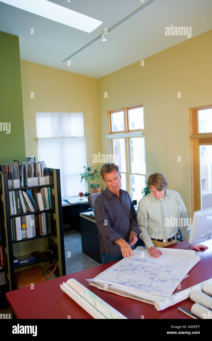 two architects in casual office with plans on table Stock Photo