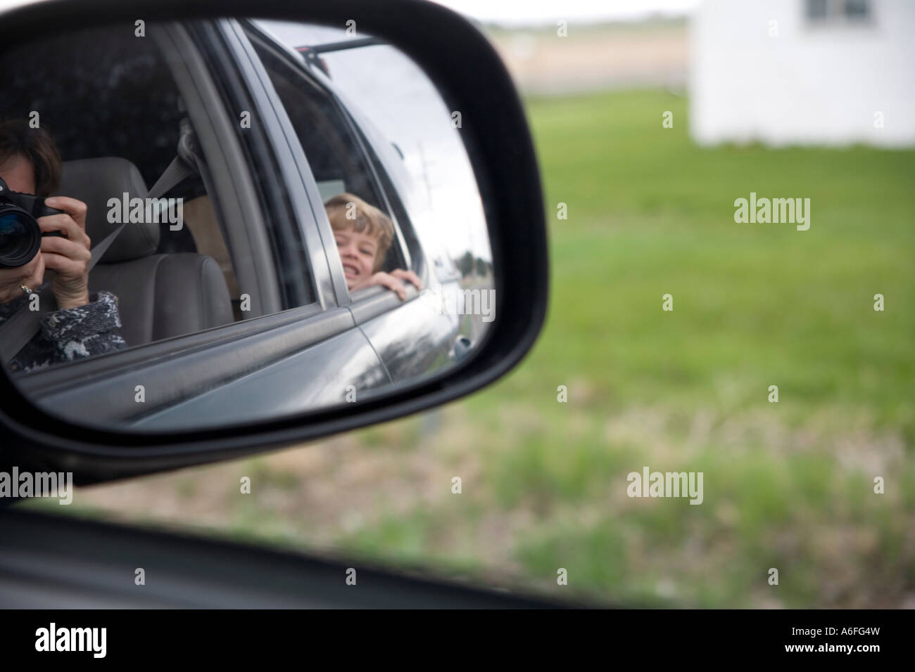 Taking photo from a car of a child in the back seat seen in rearview mirror Stock Photo