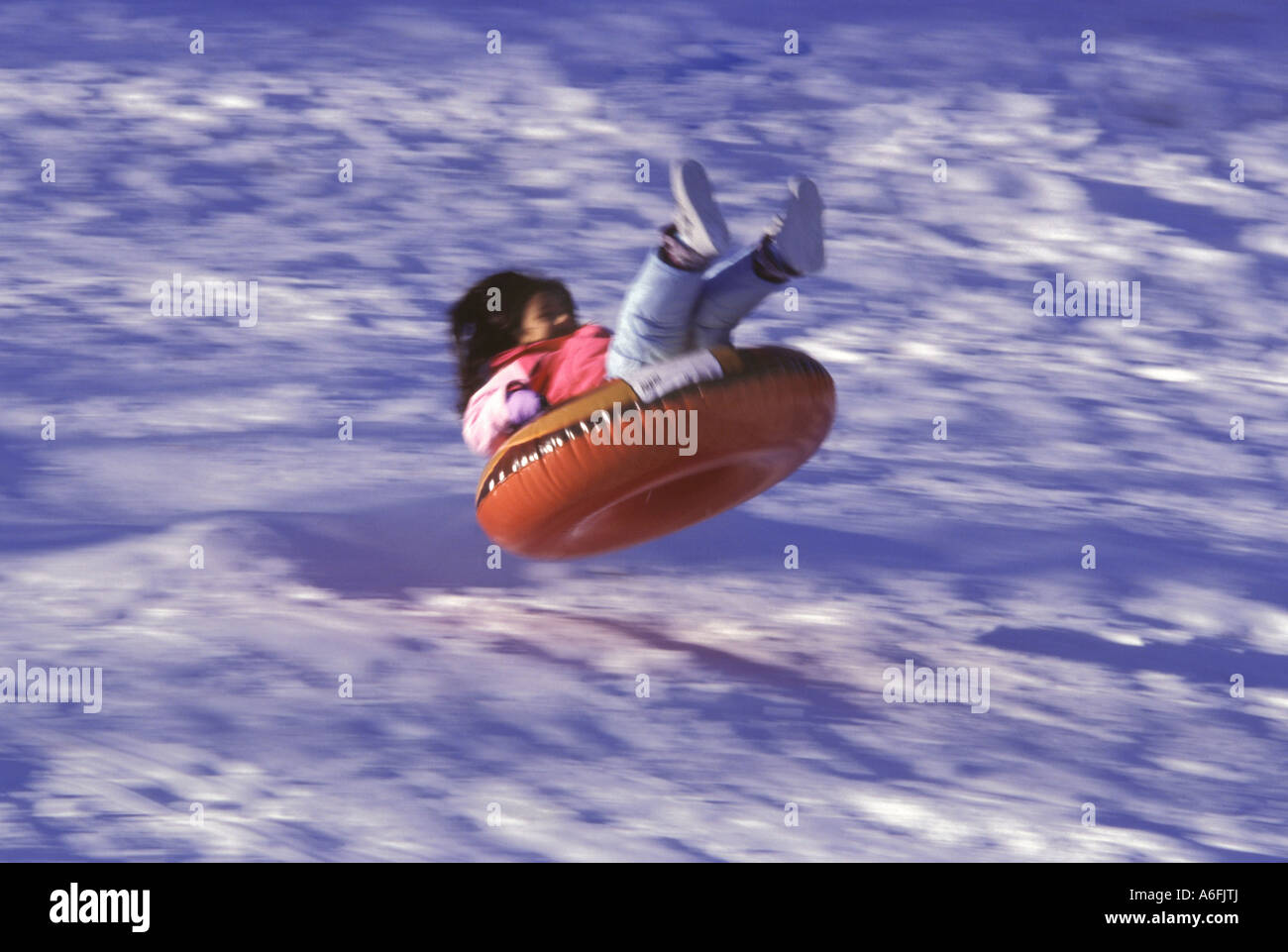 Child slides in snow on rubber inner tube toy Stock Photo Alamy