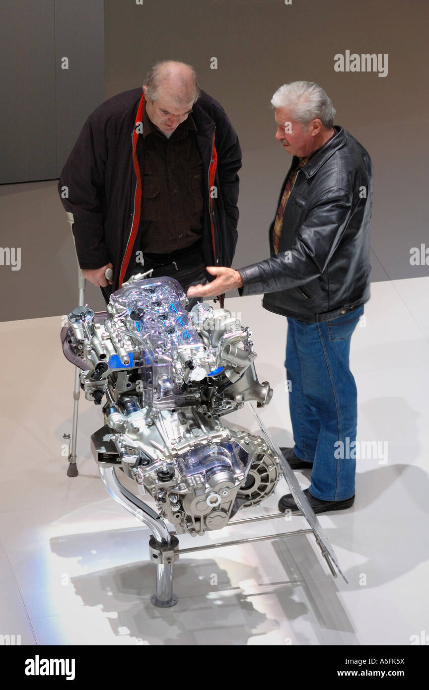 Two men examining an engine at the Geneva Motor Show. Motion blur on one man's hand Stock Photo