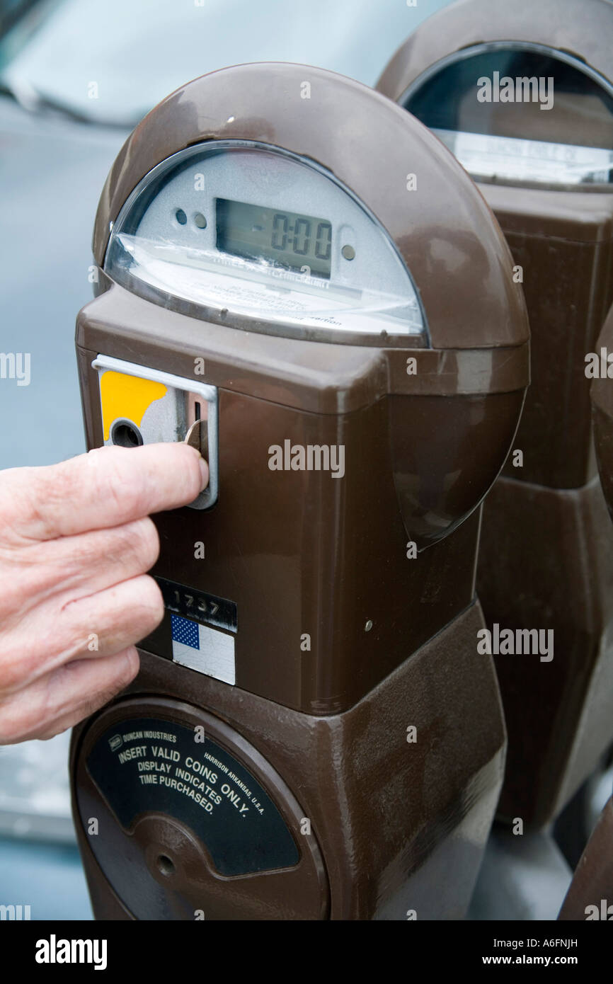 Hand feeding coin into parking meter Stock Photo Alamy