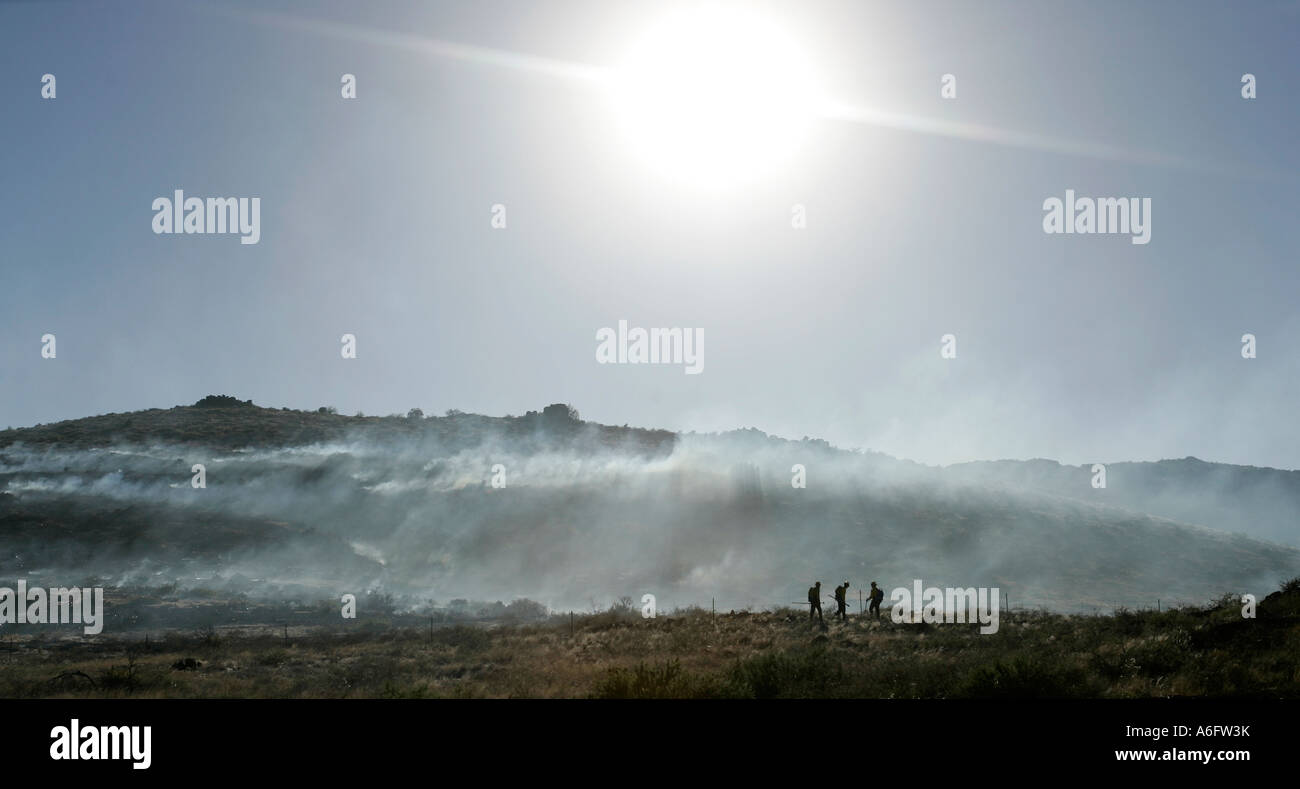 Firefighters battle a brush fire on a charred hillside under the ...