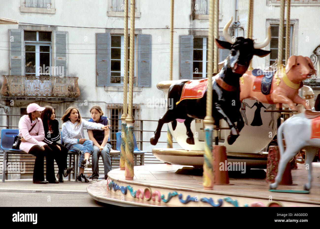 Young French girls watching a century old carousel in Arles Stock Photo