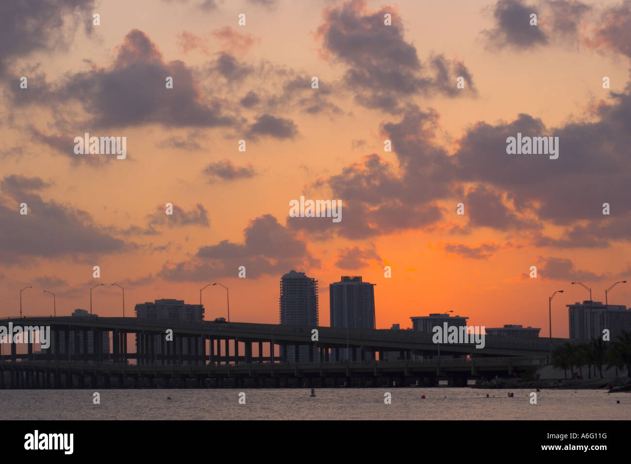 MIAMI FLORIDA USA Sun sets over water Biscayne Bay with buildings and causeway at rear Stock Photo