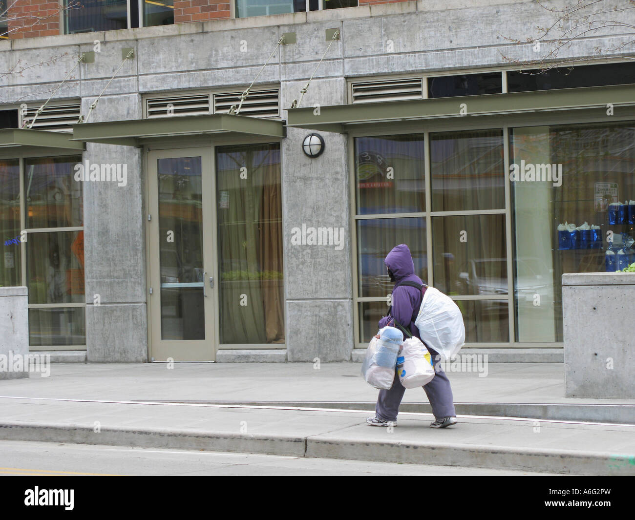 Homeless person carrying bundles of plastic sacks Seattle Washington Stock Photo
