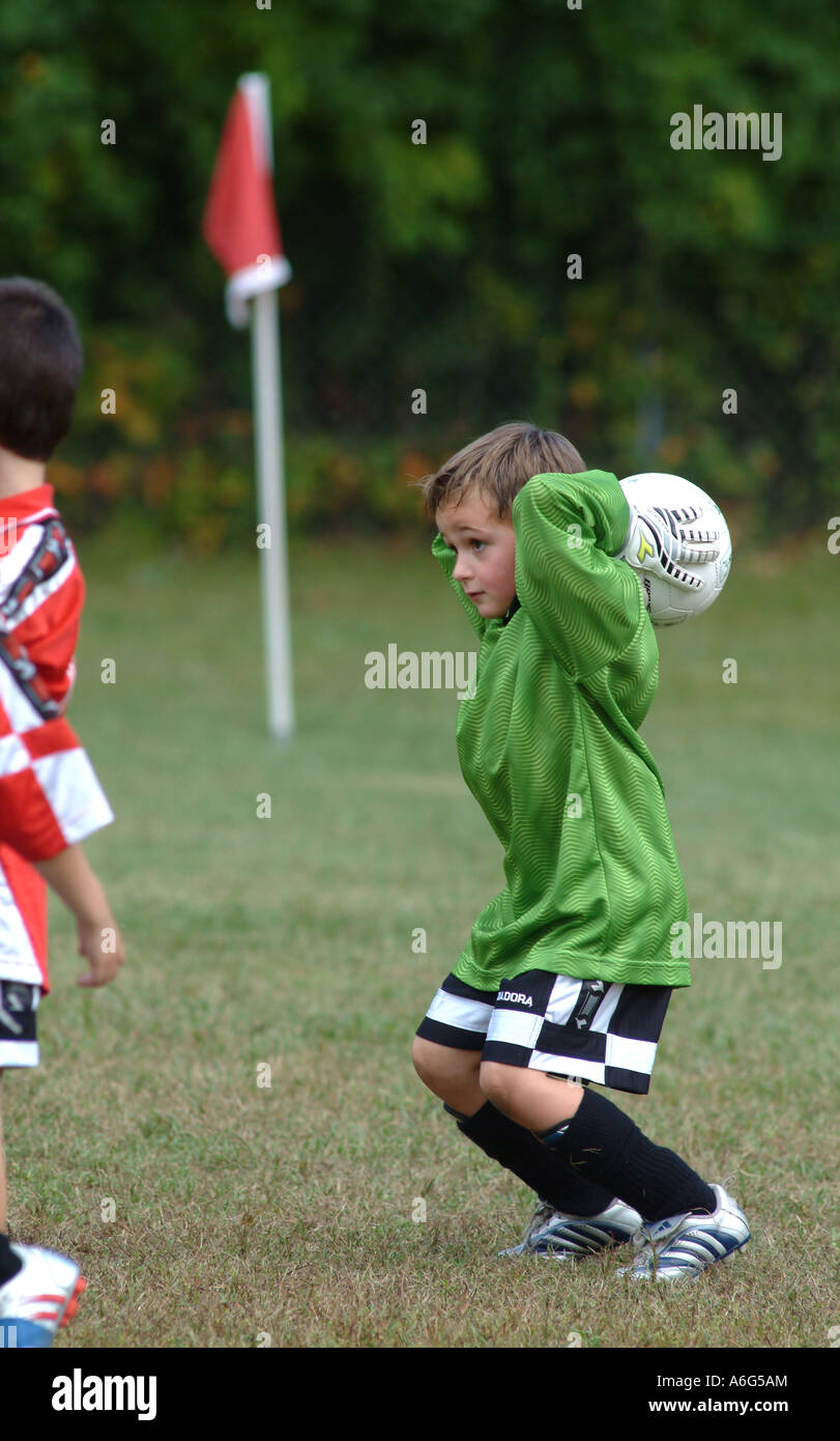 Seven year old boy throws a soccer ball inbounds during a youth soccer