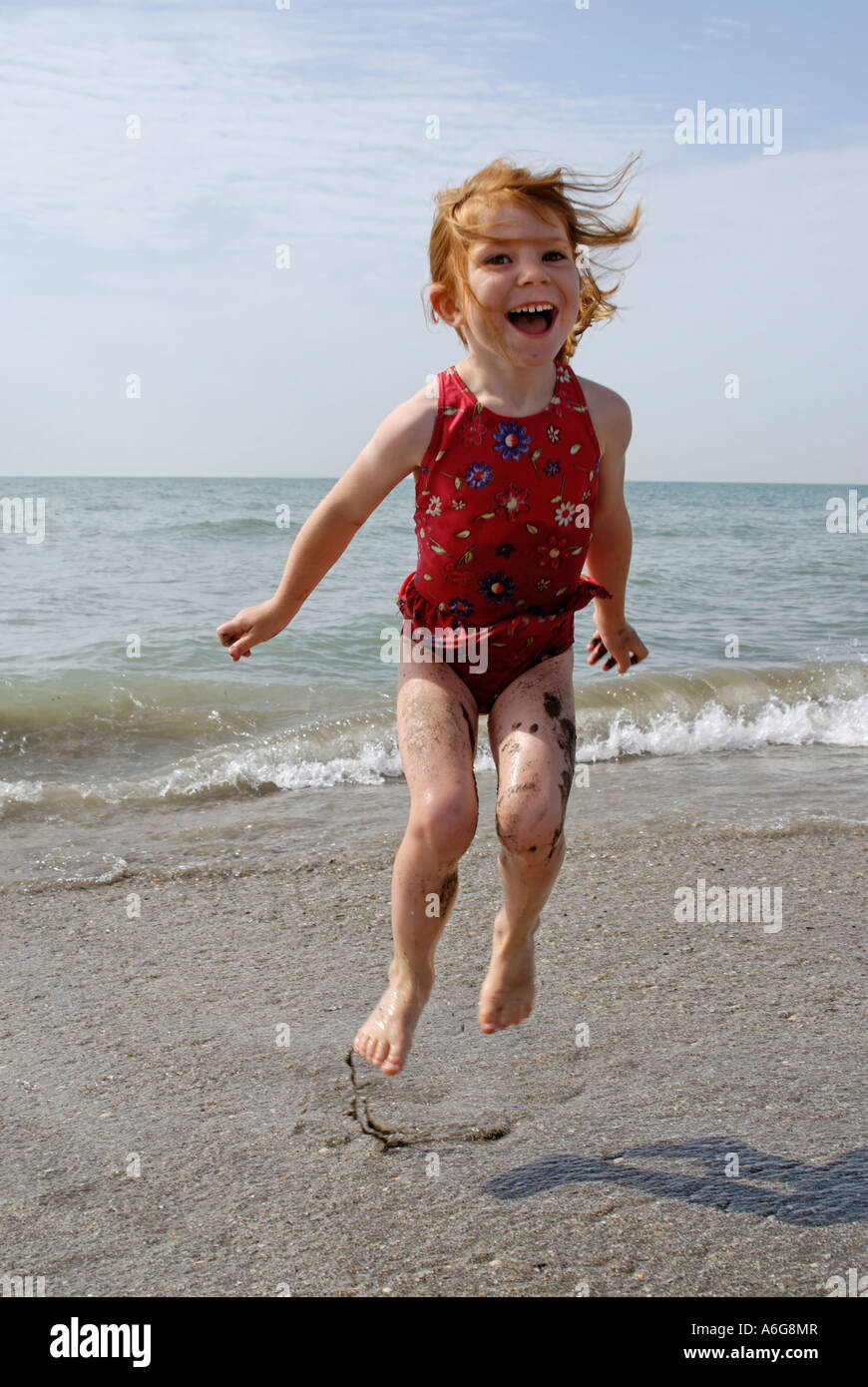 Child hops at the beach in the sea surf Stock Photo