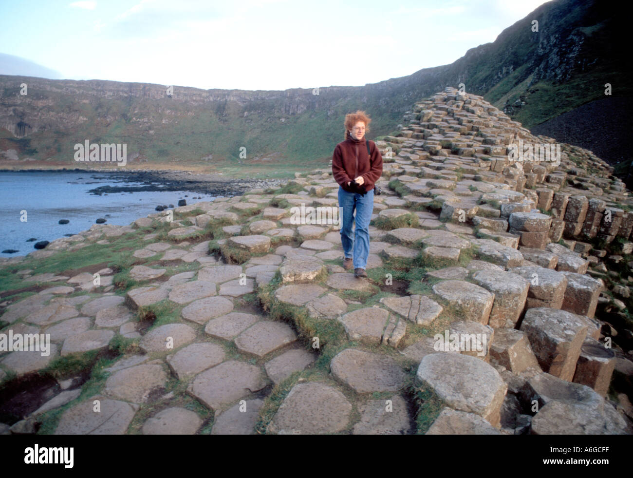 Red haired Irish woman on The Giants Causeway in Northern Ireland which are formations the same as Devils Post piles in sierra Nevada range California Stock Photo