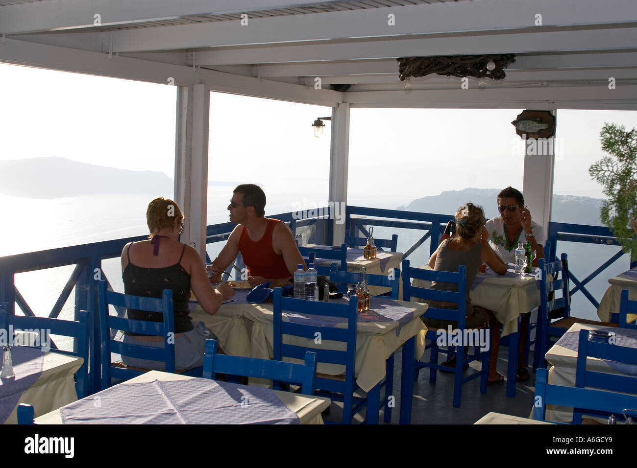 People enjoying the evening sunset views in a bar restaurant in Imerovigli Greek Island of Santorini or Thira Greece Stock Photo