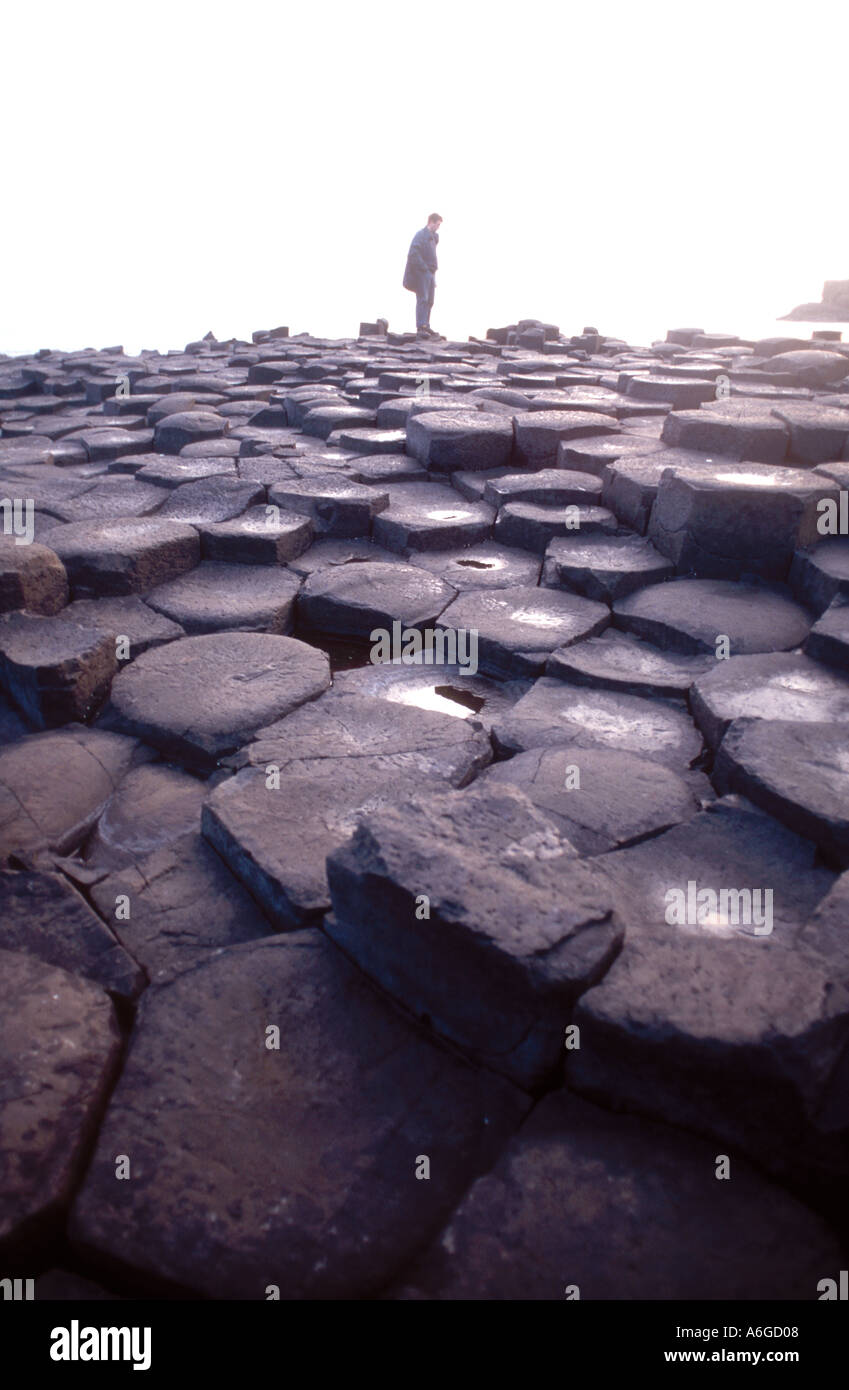 Red haired Irish woman on The Giants Causeway in Northern Ireland which are formations the same as Devils Post piles in sierra Nevada range California Stock Photo