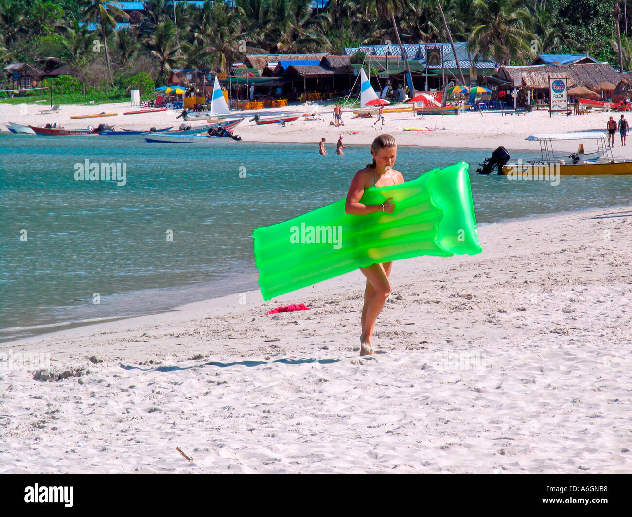 Young woman walks on beach with green air mattress Perhentian Kecil Malaysia Stock Photo