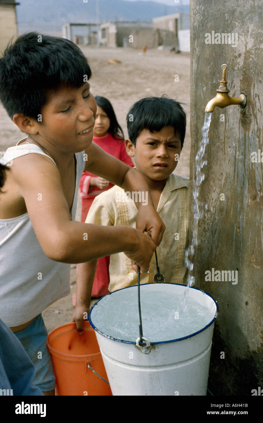 Children getting water at public tap at a shanty town which are called pueblos jovenes on the outskirts of Lima Peru Stock Photo