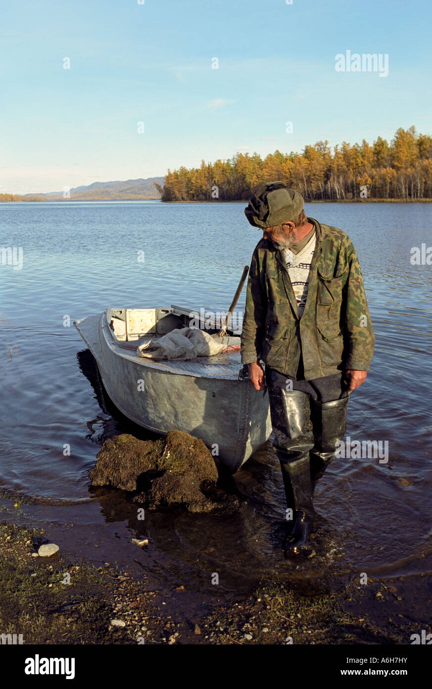 Fisherman is dragging a boat out of a river. Azas (Todja) lake. Todja Kozhuun. The Sayan Mountains. The Tyva (Tuva) Republic. Ru Stock Photo
