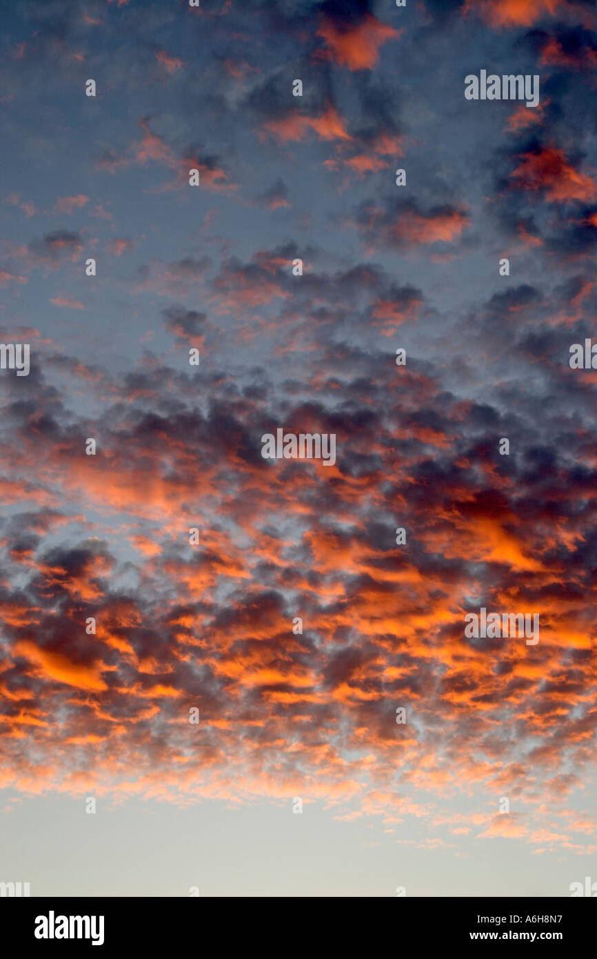 Sunset grey clouds with pink sunlight underneath against pale blue sky over London England Stock Photo