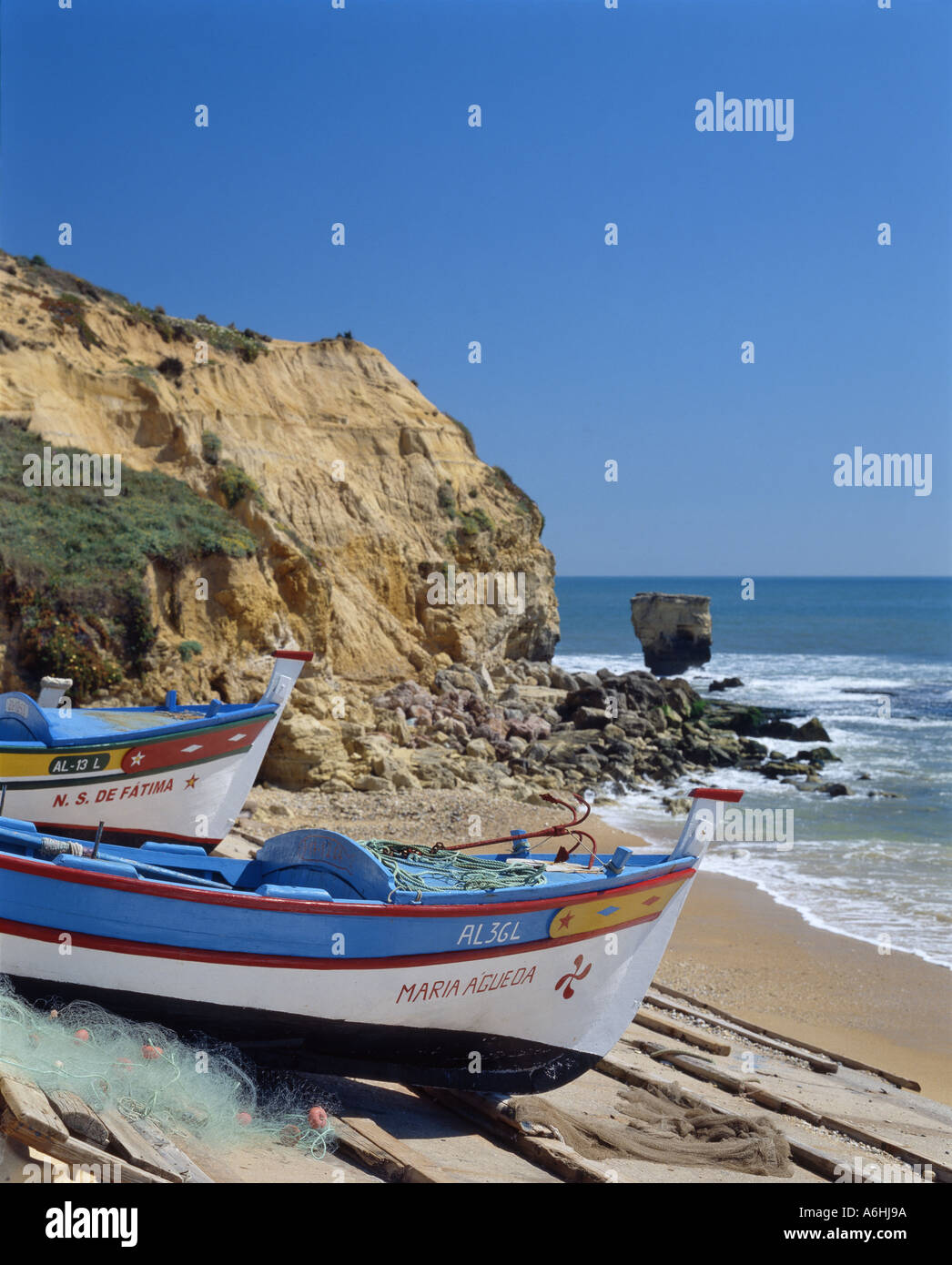 Portugal the Algarve, Olhos de Agua, fishing boats drawn up on beach, cliff in background Stock Photo