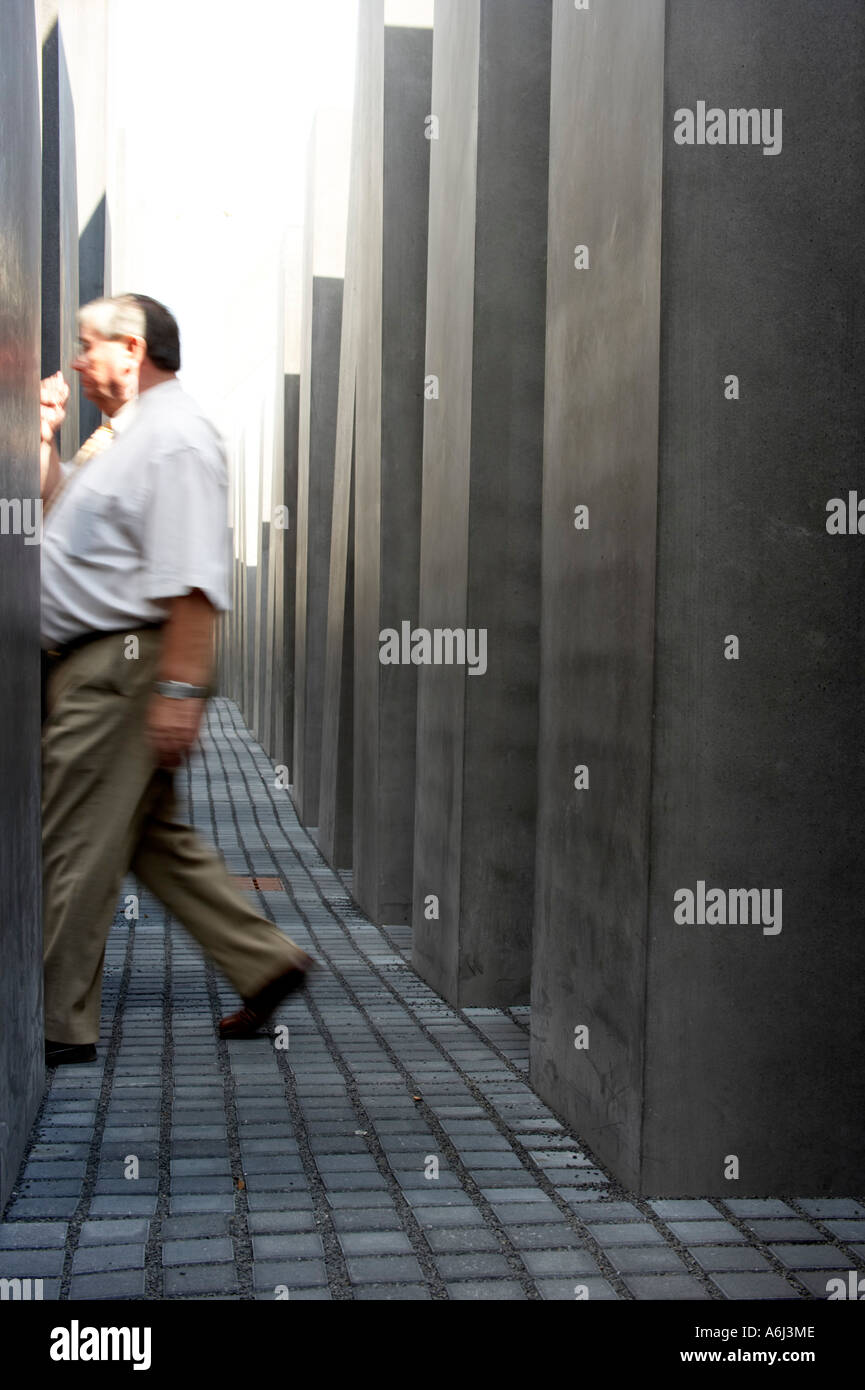 A man walks in the middle of the Holocaust memorial between the concrete steles, Berlin, Germany Stock Photo