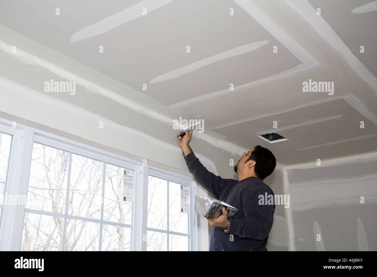 Immigrant Worker Applying Drywall Joint Compound Building 1