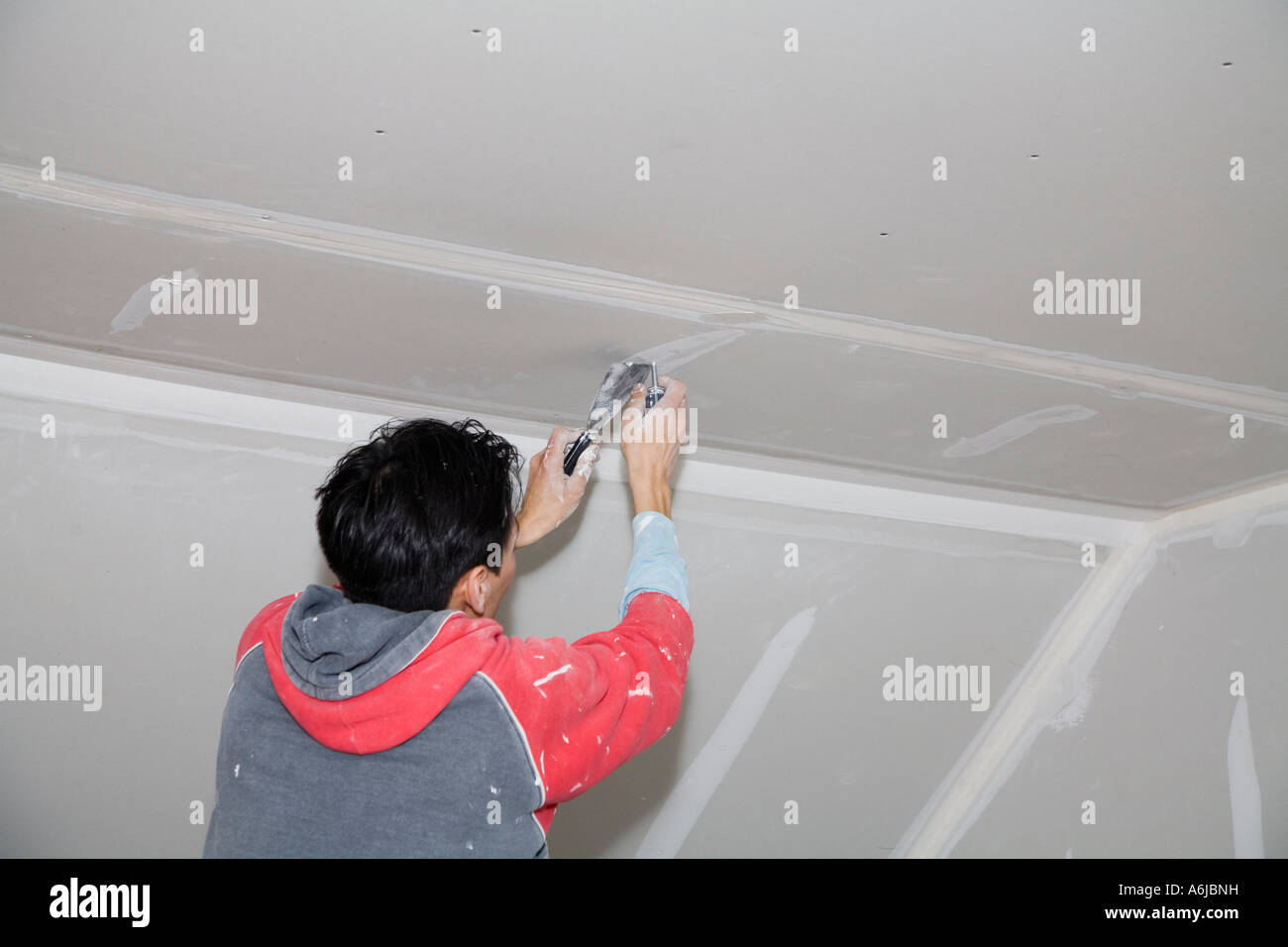 Immigrant Worker Applying Drywall Joint Compound Building 1
