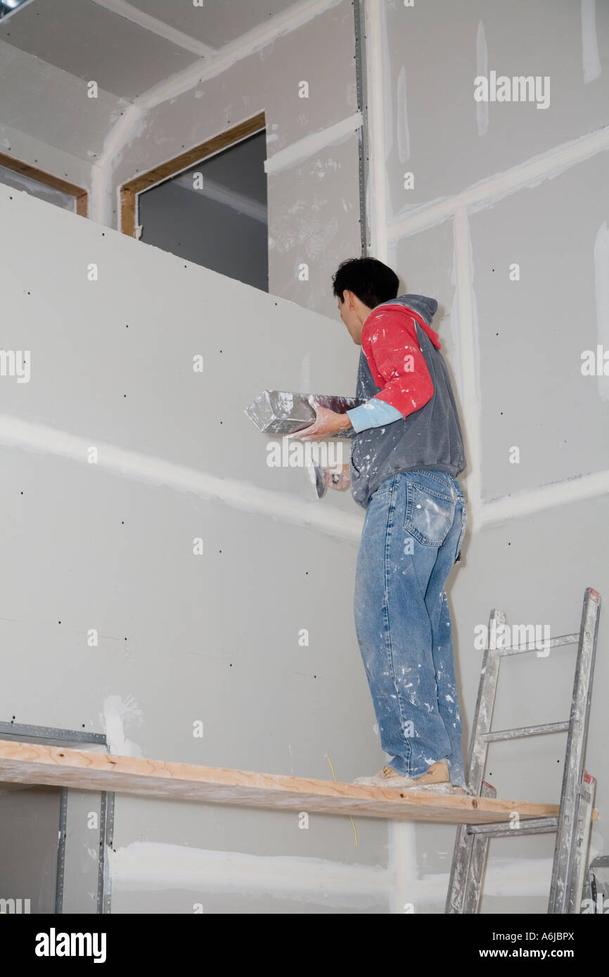 Immigrant Worker Applying Drywall Joint Compound Building 1