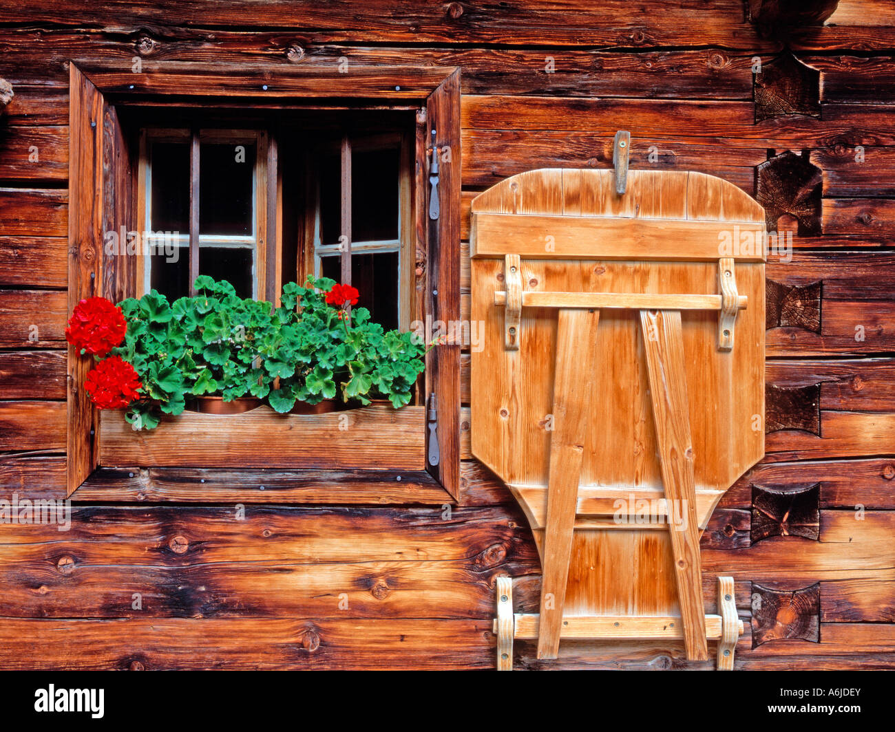 Window of a wooden alpine hut decorated with Geraniums. Austria Stock Photo