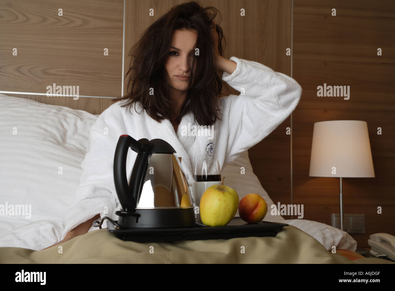 dozy young woman sitting in bed with a breakfast tray in her lap Stock Photo