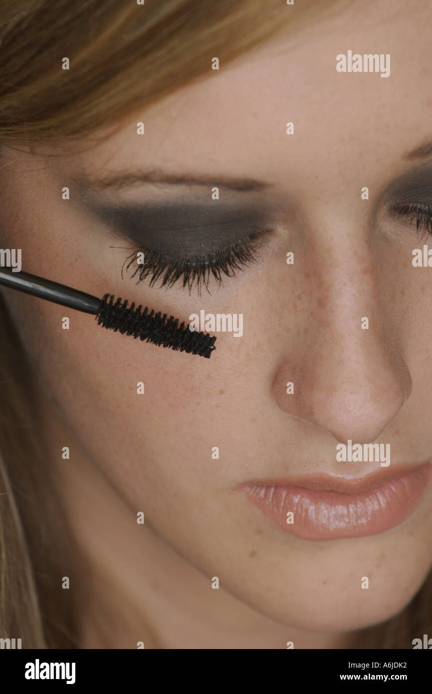 young woman putting on mascara Stock Photo Alamy