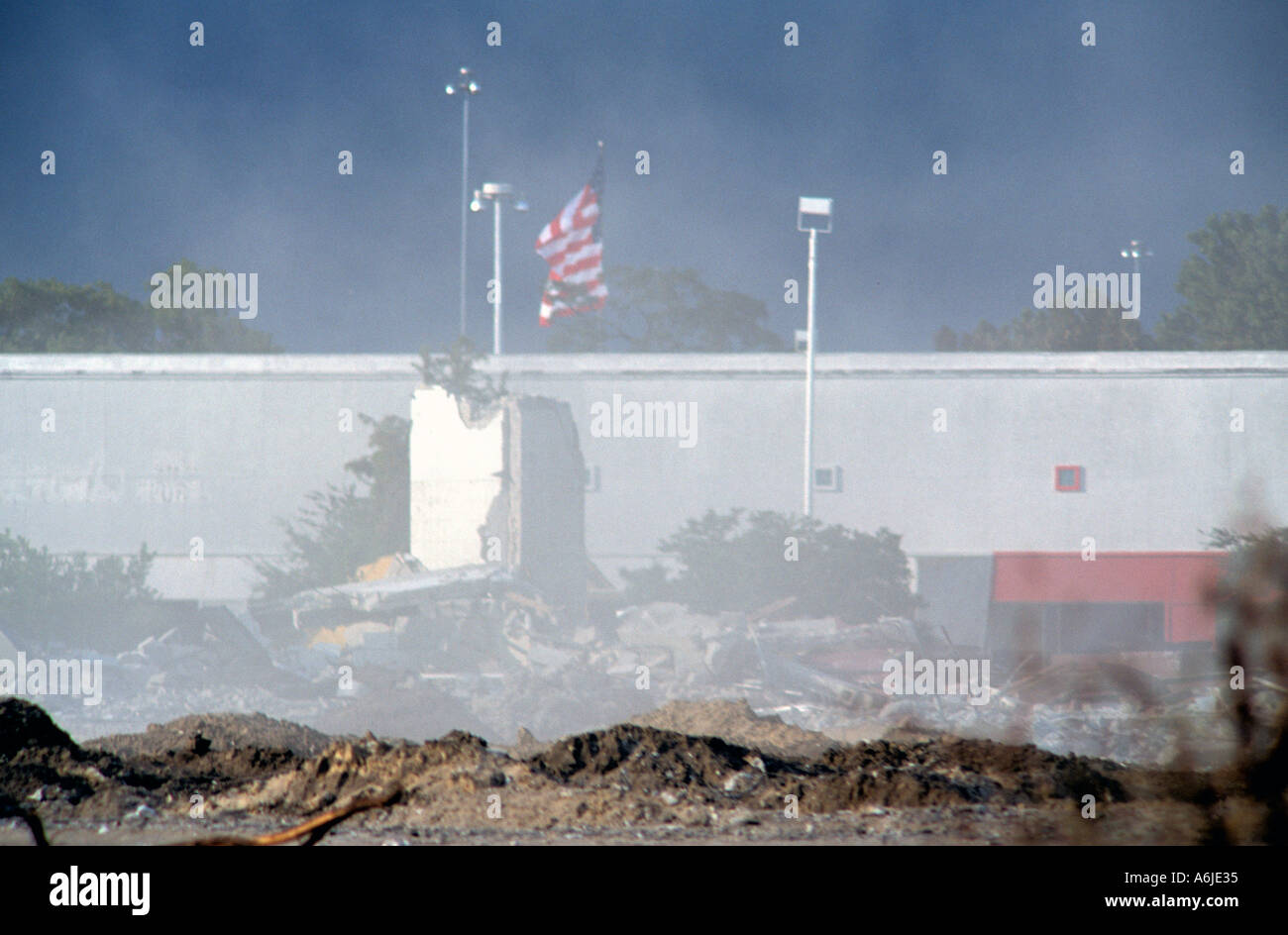 Dust and sand blow by the destruction of an American Mall with the American flag in the background Stock Photo