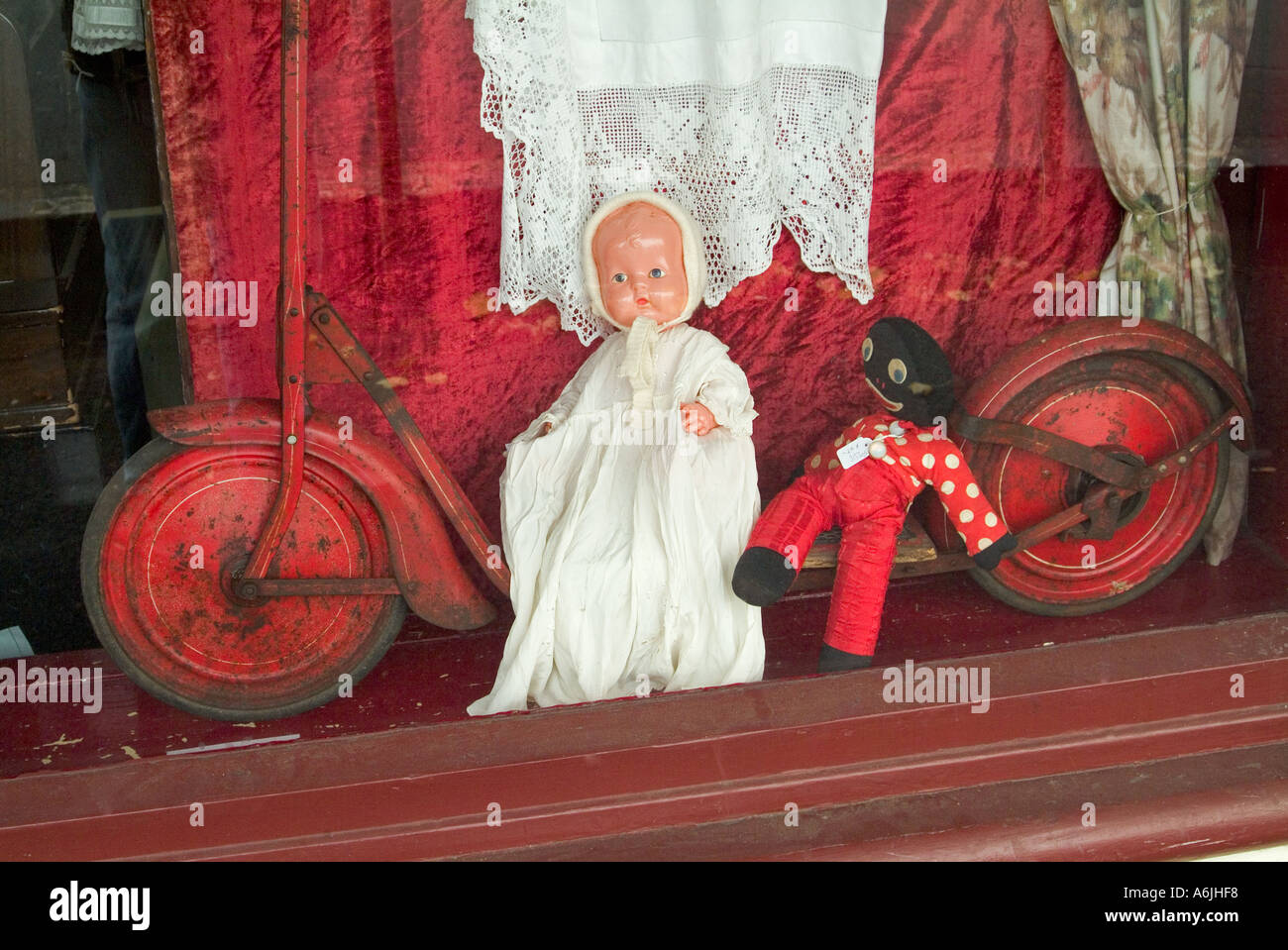 Antique shop window displaying doll old scooter and golliwog Stock Photo