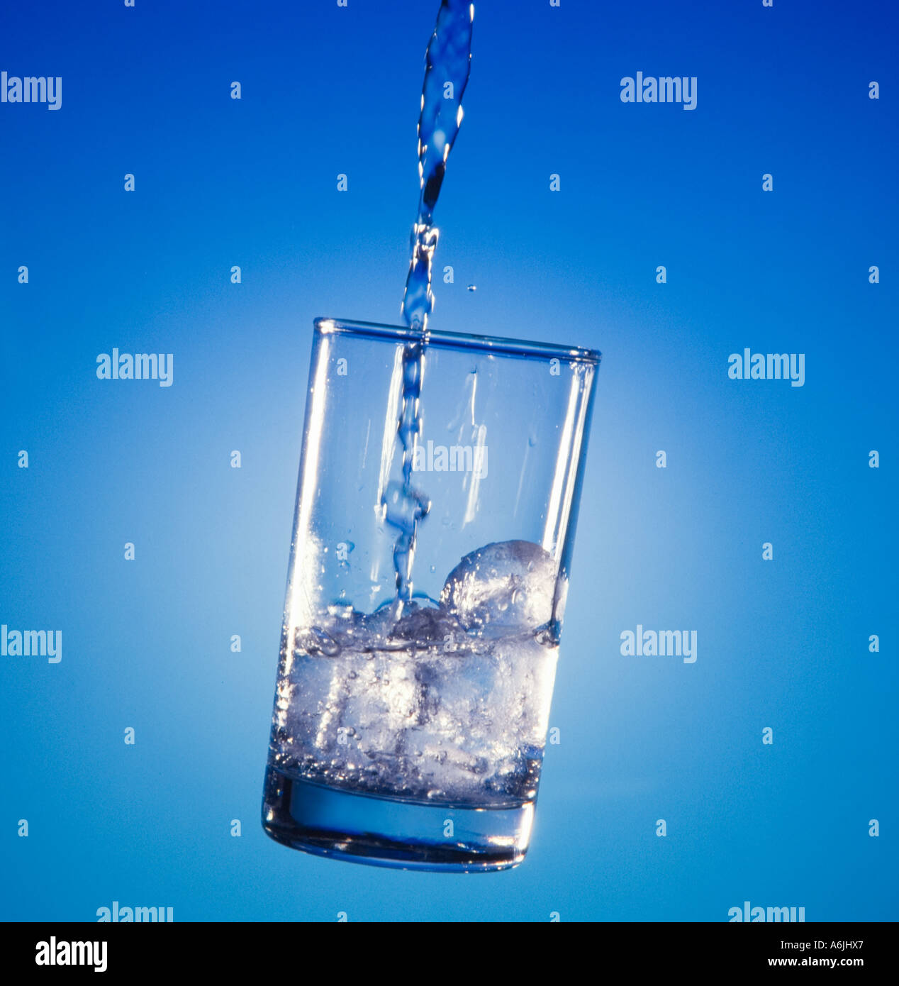 Water pouring into glass  floating on blue background Stock Photo