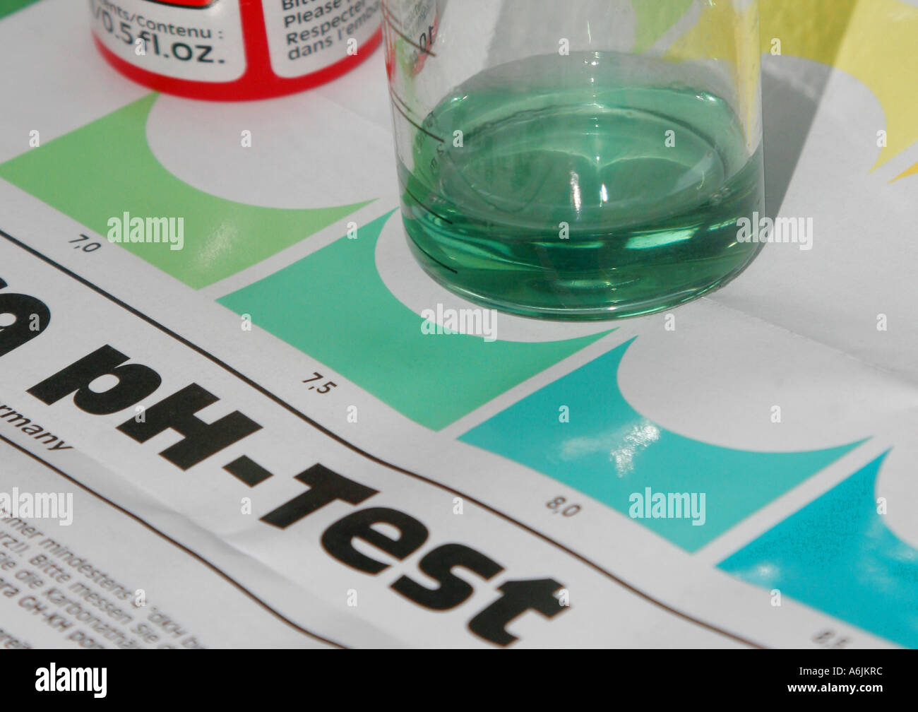 ph-value ph test, measuring cup with green coloured test liquid standing on test sheet Stock Photo