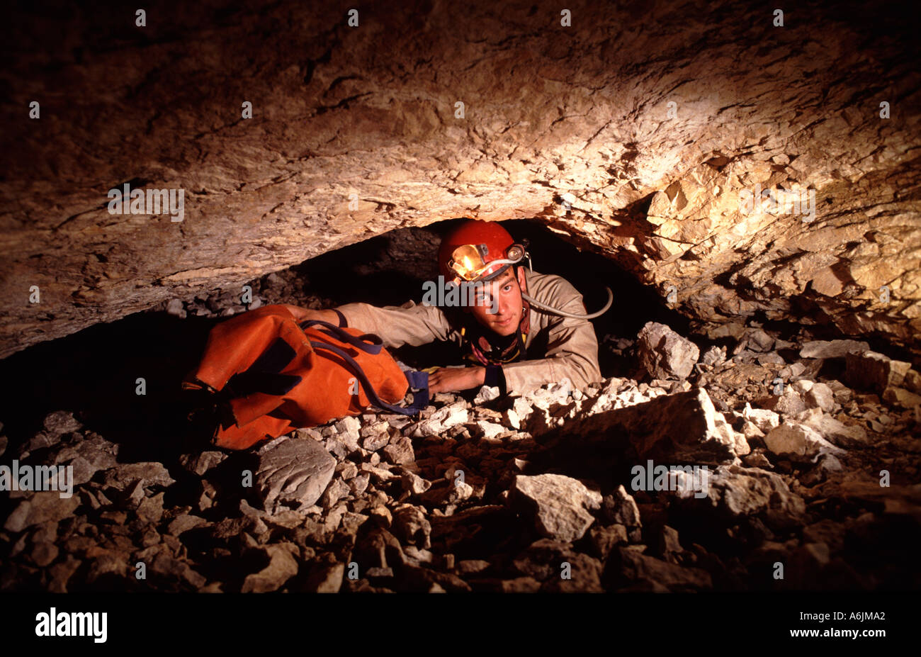 A caver negotiates a tight squeeze in a cave on Migovec mountain Slovenia Stock Photo