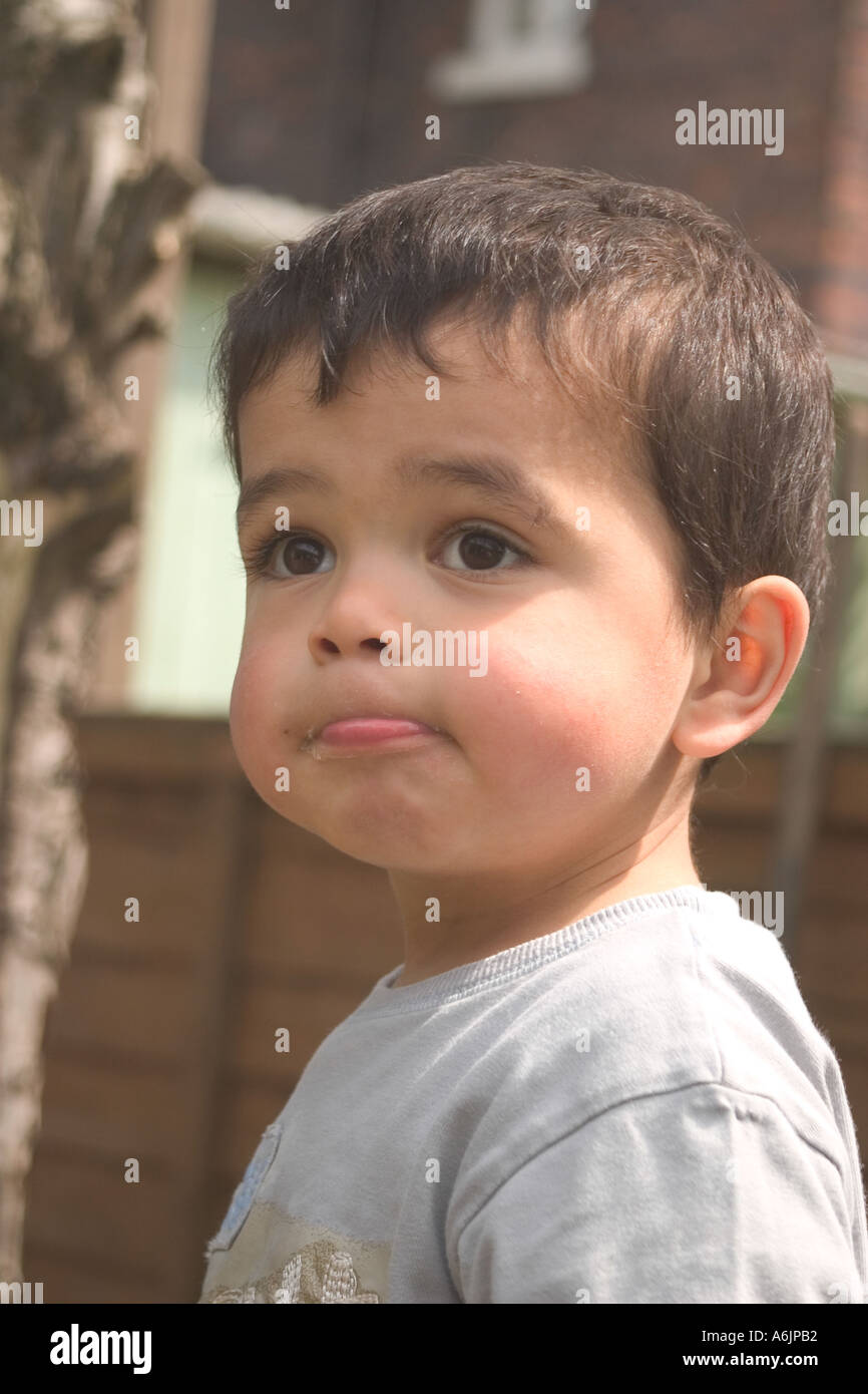 young boy of mixed race parents in garden thinking Stock Photo