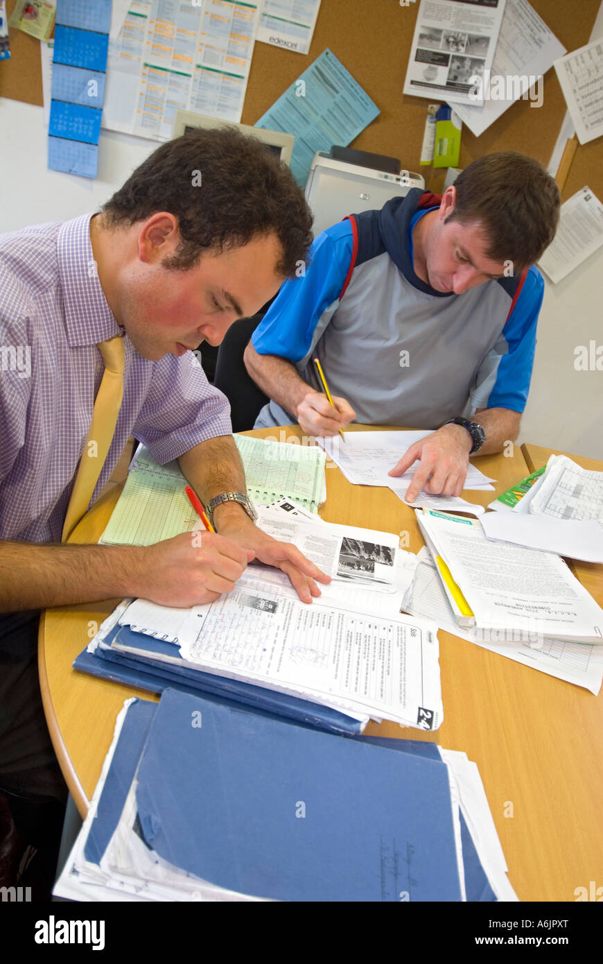 Teachers marking papers in school. Assessing and marking students school exam work in staff room at school facility Stock Photo