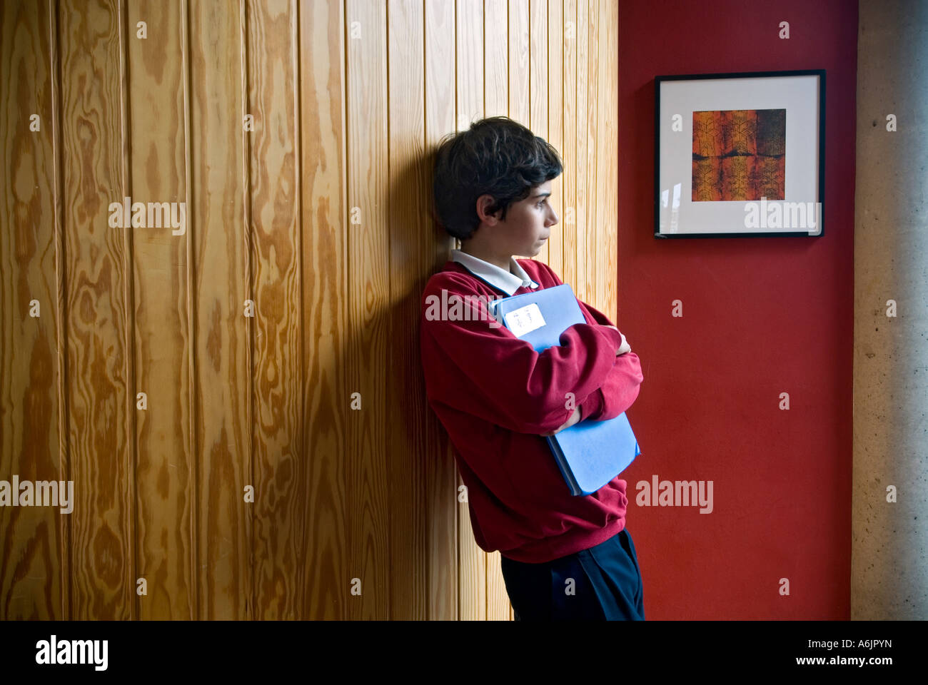 Junior schoolboy pensively waiting alone in school corridor Stock Photo
