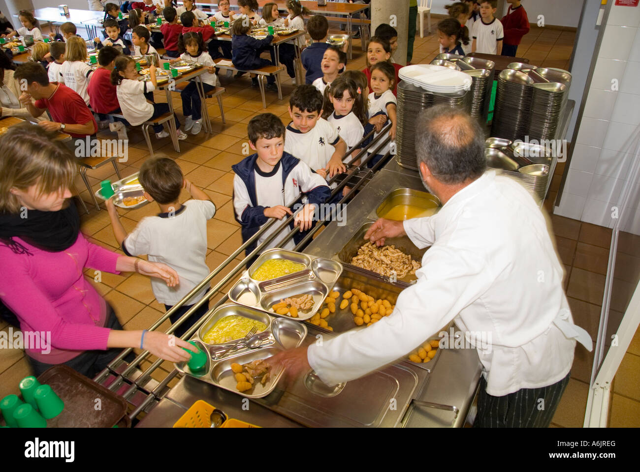 SCHOOL MEALS LUNCH CANTEEN SERVICE DINNERS HEALTHY service junior and  infant school children in busy school canteen with chef and teacher  supervising Stock Photo - Alamy