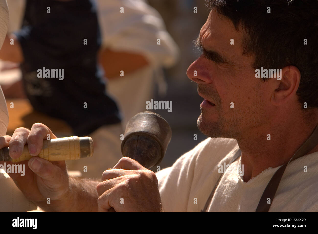 French Stonemason, man in french period costume carving stone in closeup,using mallet and chisel at medieval festival, Monflanquin Aquitaine france eu Stock Photo