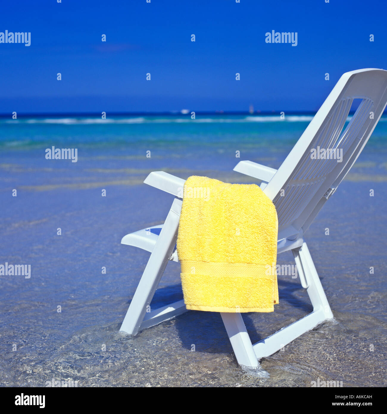 WHITE CHAIR AND YELLOW TOWEL AT THE BEACH WITH NO PEOPLE Stock Photo