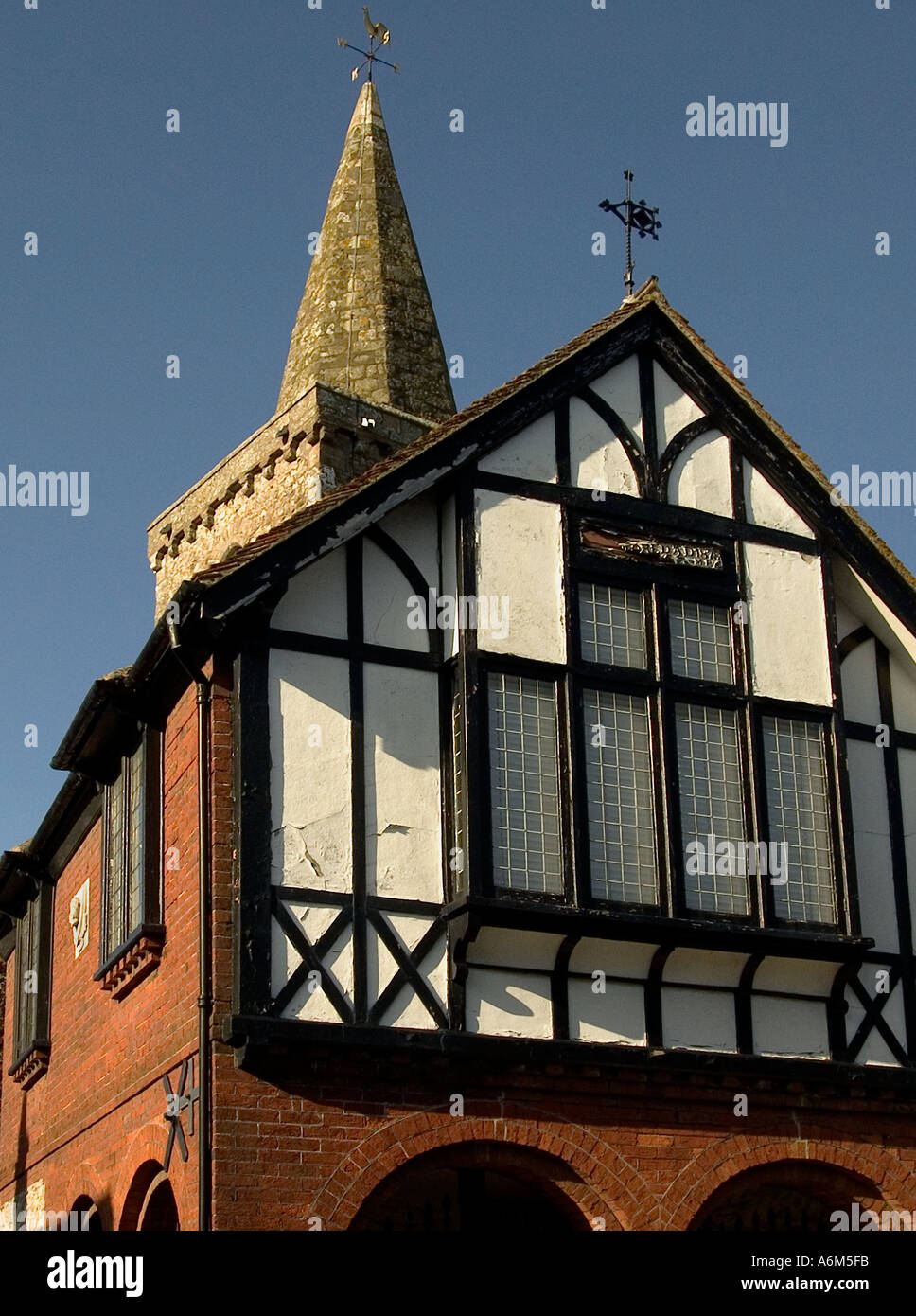 Brading Old Town Hall, half-timbered building with weather vane, projecting window, cracked infill, St Mary's church spire behind, Isle of Wight, UK Stock Photo