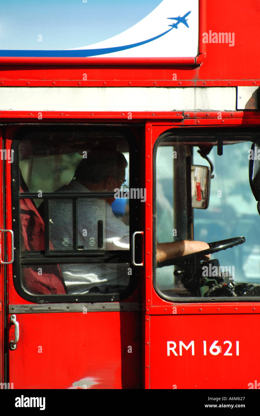 Summer day close up side view of driver in cab man at work driving classic historical red double decker London Transport Routemaster bus England UK Stock Photo