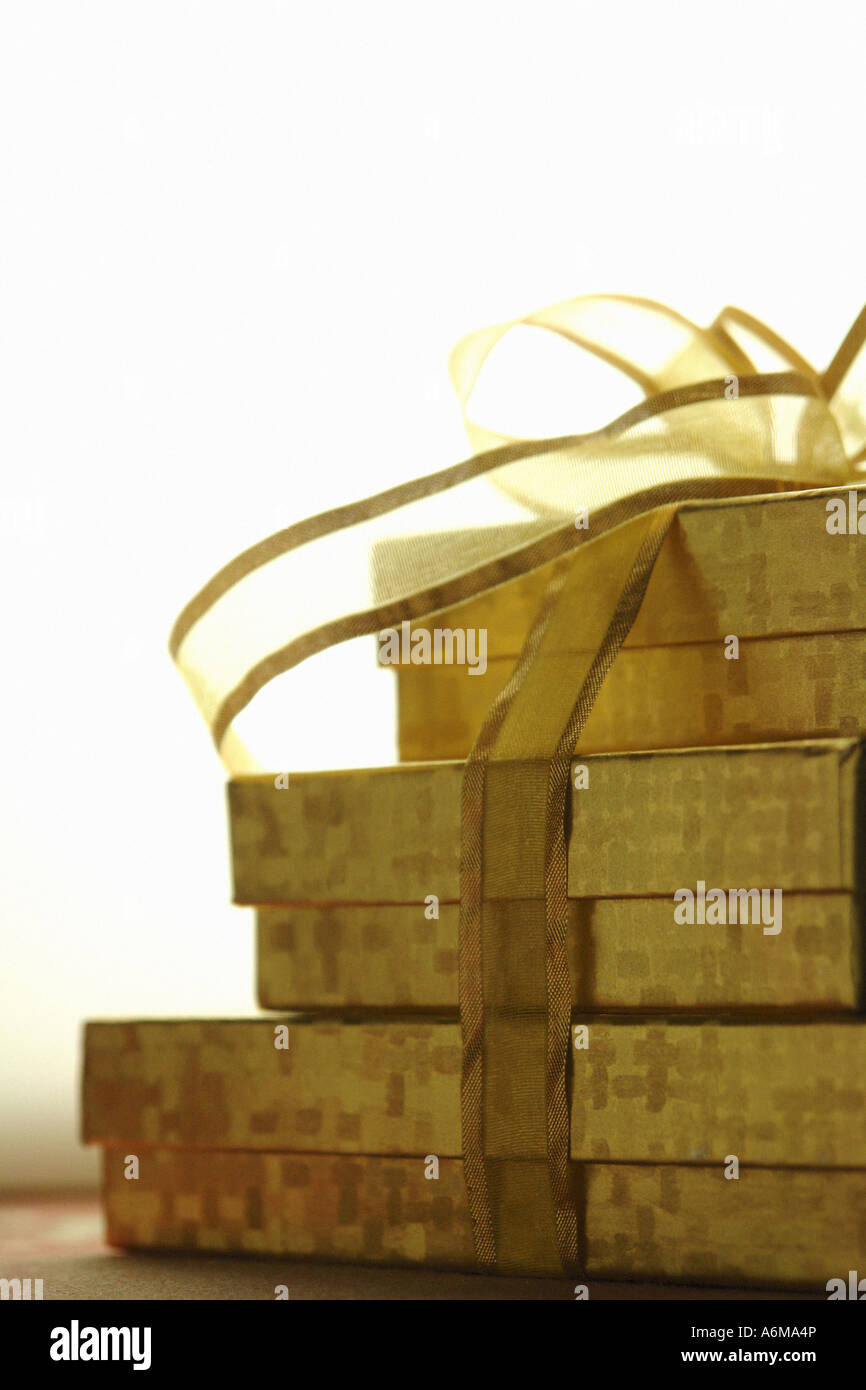 Stack of Three 3 Gold Gift Boxes Tied Together with Gold Ribbon Copy Space Stock Photo