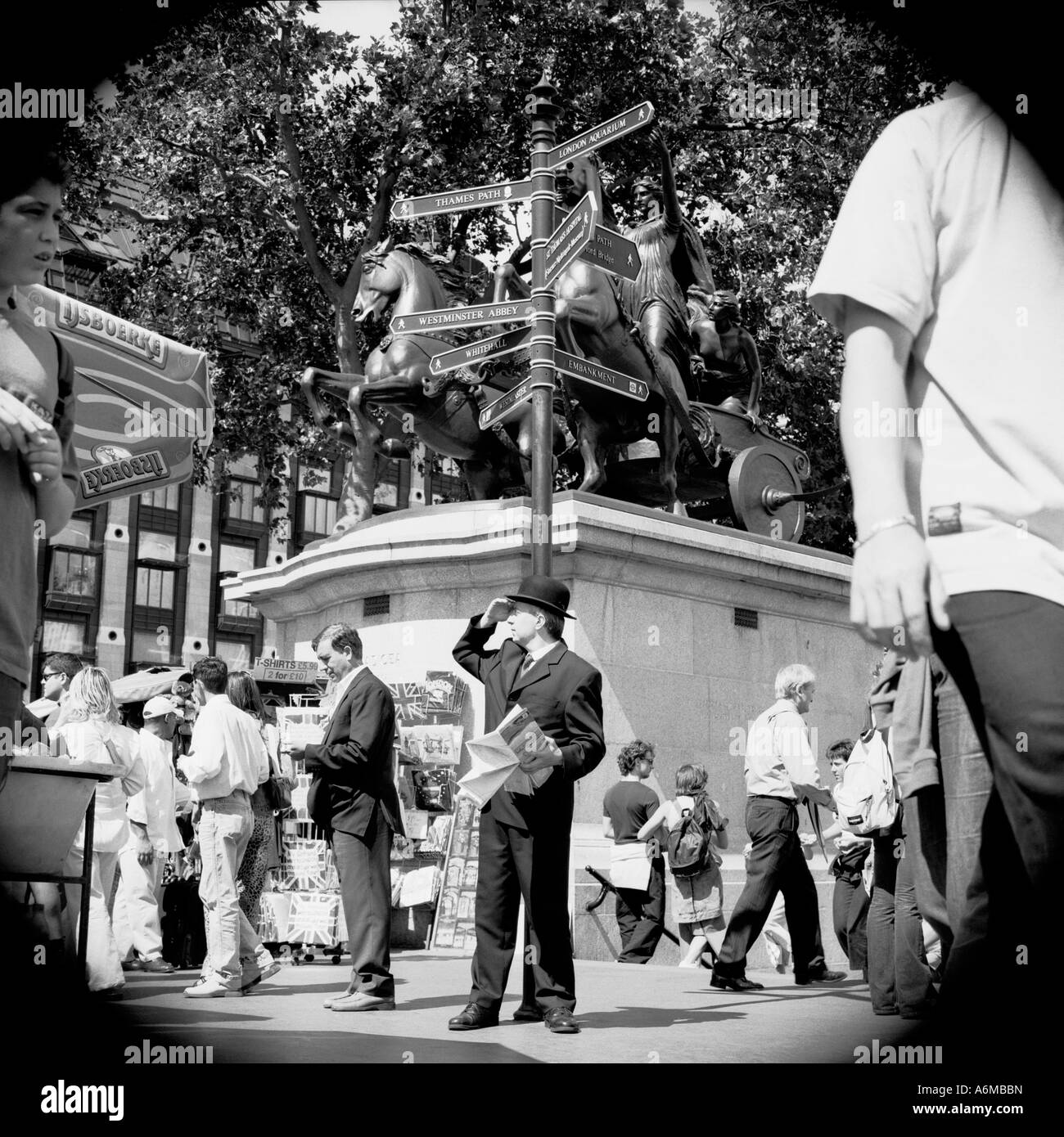 Lost in London. Man in bowler hat looking around by signpost holding map. Stock Photo