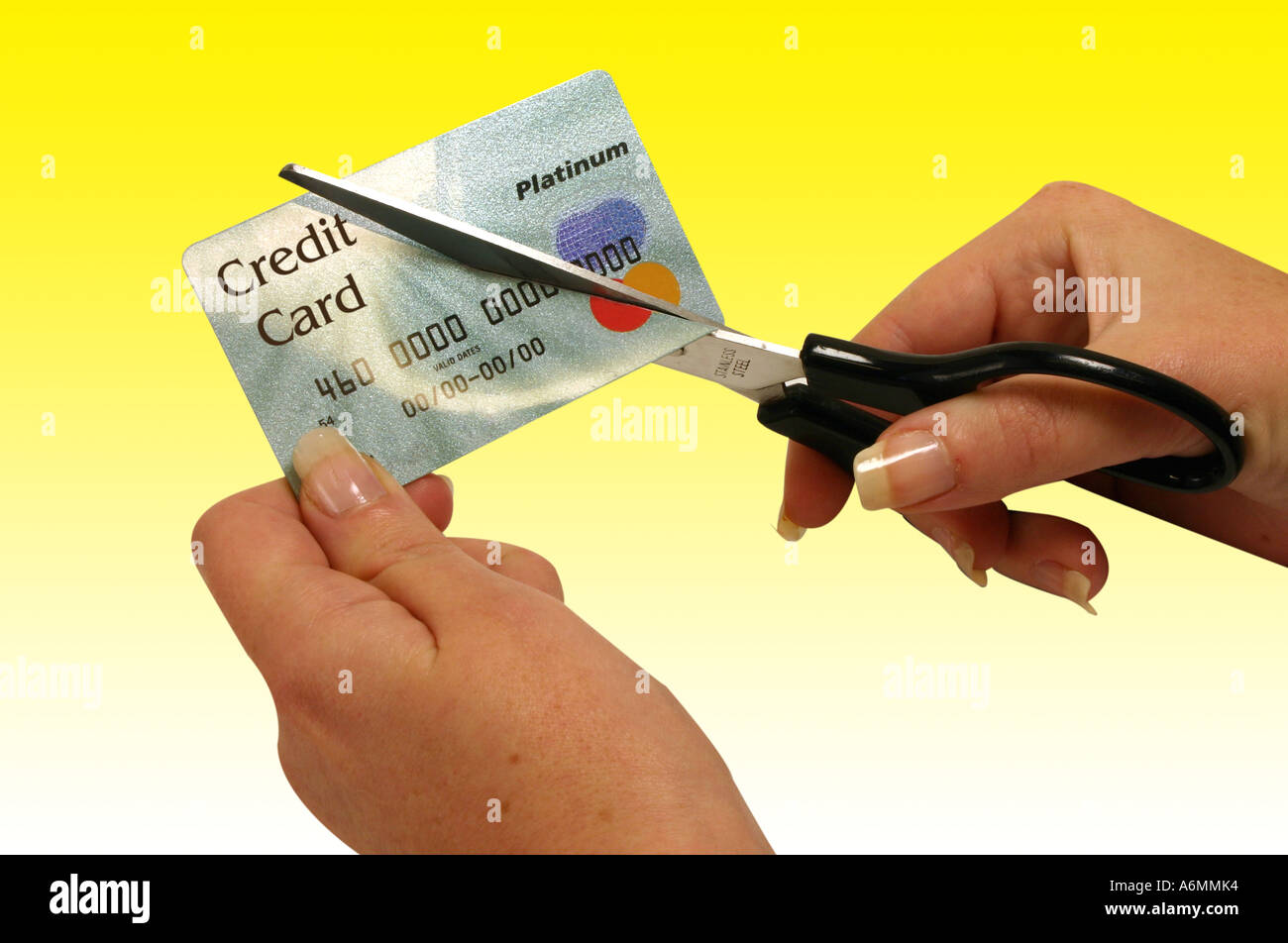 Credit card held by woman being cut in half by scissors Stock Photo Alamy