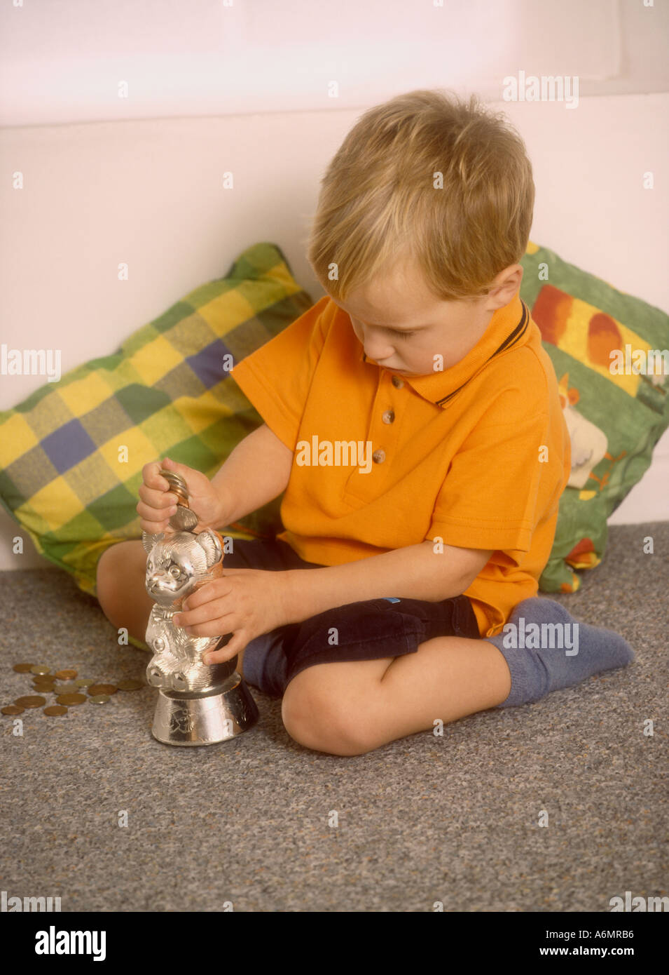 Young boy putting coins into a money box Stock Photo - Alamy