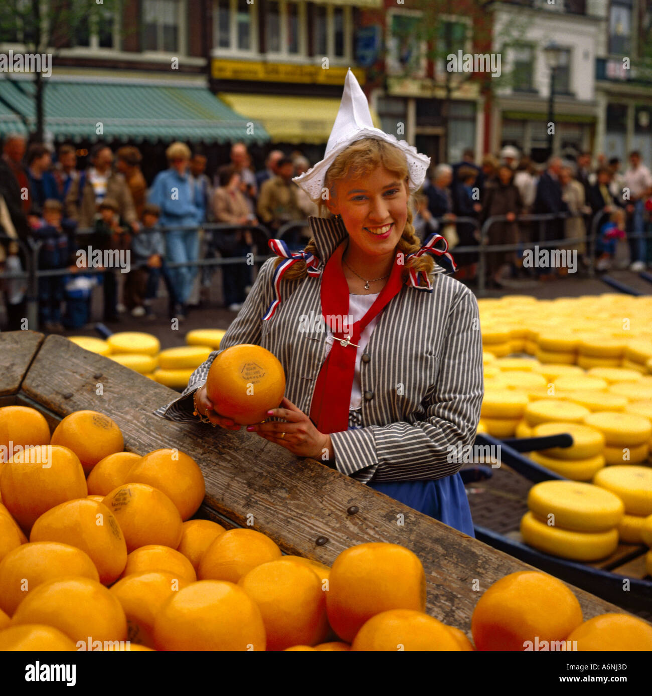 Smiling Dutch girl in national costume holding round Edam Cheese at ...