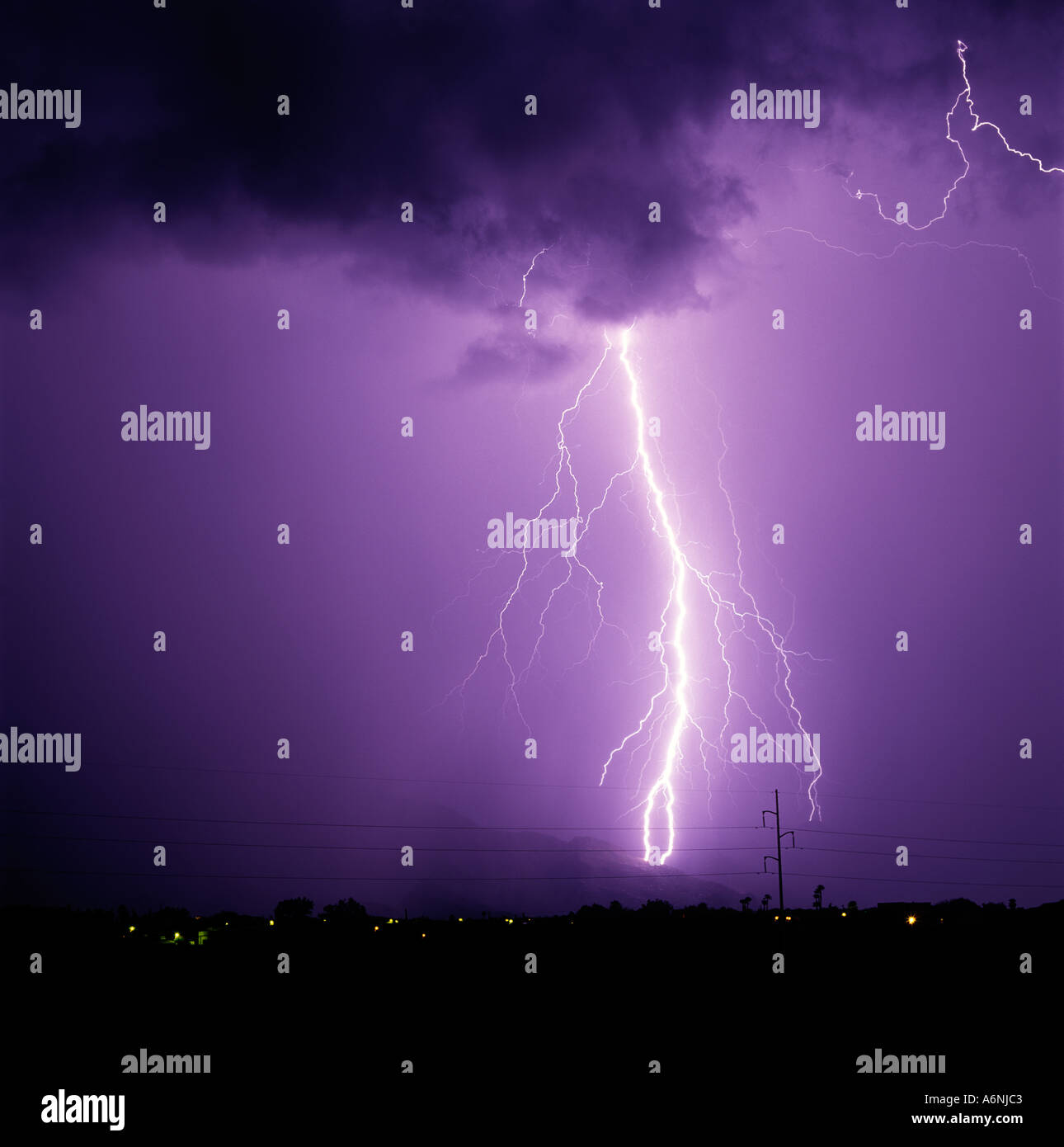 A large lightning bolt strikes down from a purple sky in the Catalina Foothills in Tucson Arizona, USA. Stock Photo