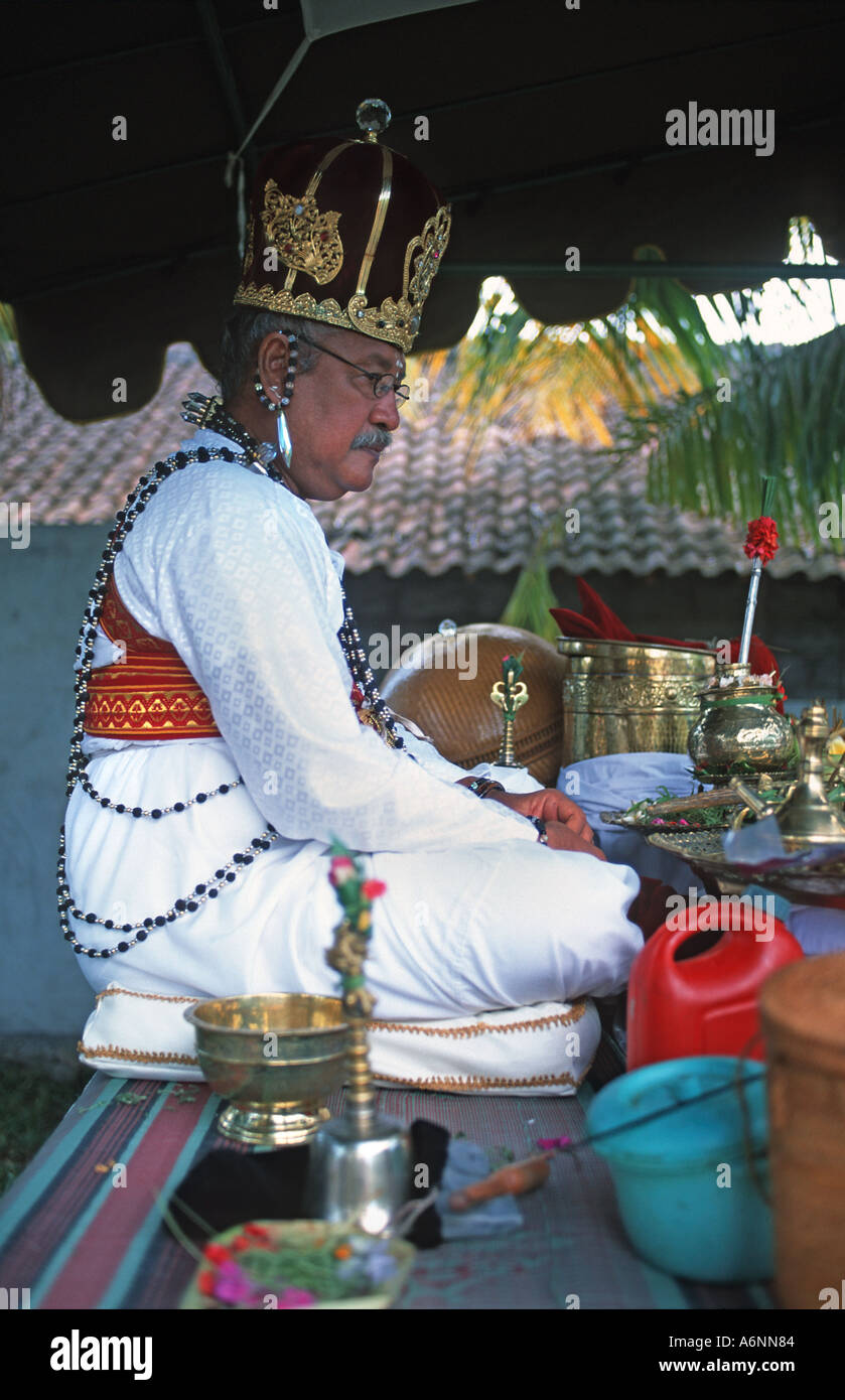 Hindu priest at a house blessing ceremony seated amongst his religious paraphernalia Renon Denpasar Bali Indonesia Stock Photo