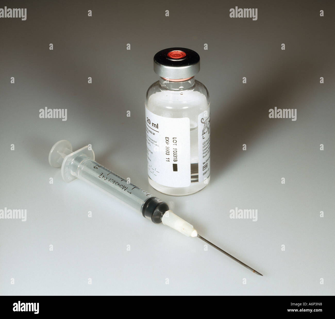 Hypodermic syringe alongside dispensary bottle of an injectable drug Stock Photo