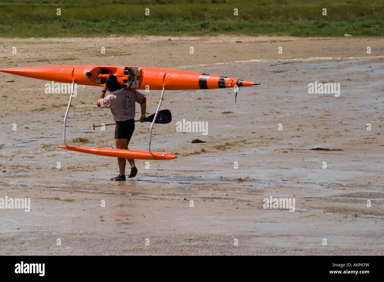 Man carrying outrigger canoe back up beach from river St Valery sur Somme  Somme Picardy France Stock Photo - Alamy